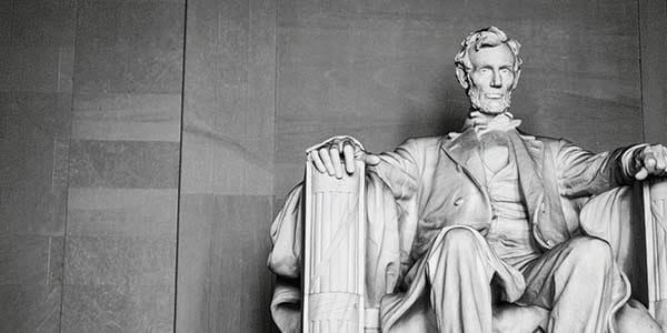 A black-and-white image of the state of Abraham Lincoln seated in the Lincoln Memorial.