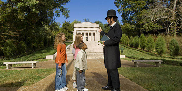 An Abe Lincoln re-enactor chats with three small children.
