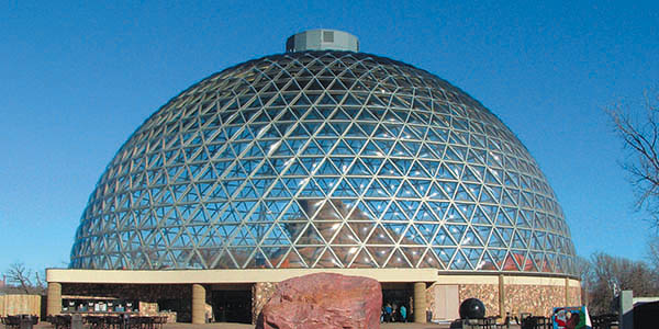 A geodesic dome with transparent triangular panels that provide views into a rock formation.