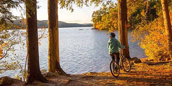 A cyclists pauses to look out over a lake during sunset.