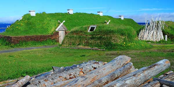 Green Sod used as a roof for a viking house with door and chimneys.
