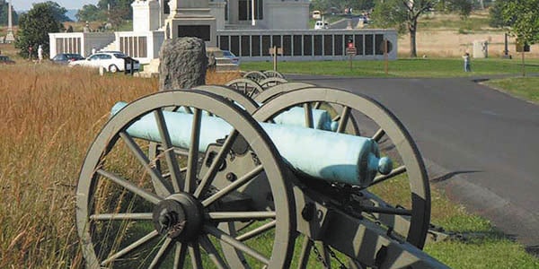 A Civil War-era cannon on a roadside that leads to a monument.