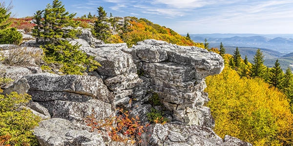 A rugged rock outcropping surrounded by golden and crimson trees.