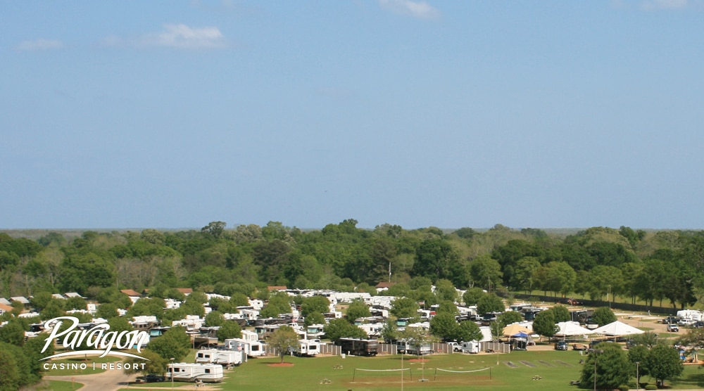 Aerial view of many RVs and Trailers camped at resort with lush greens in background