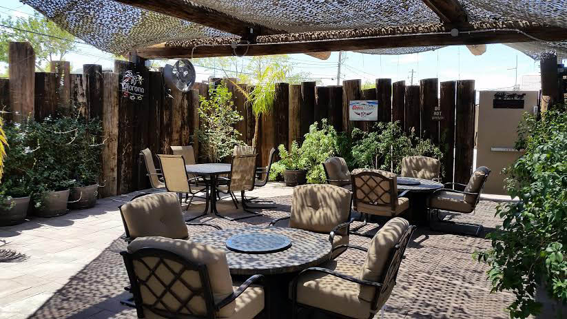 Outdoor patio area of restaurant with three tables and comfortable chairs 