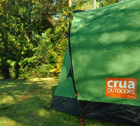 Green Crua tent pitched in lush green forested area