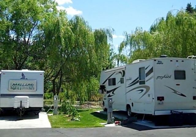 Two RV units in RV spaces, plugged in. Greenery around RVs