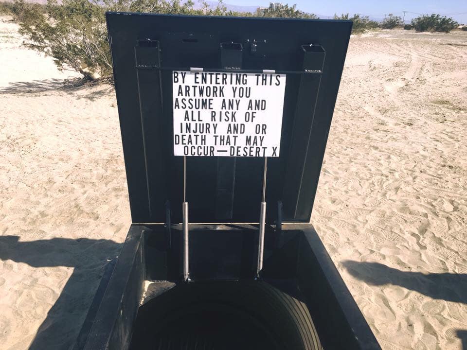 Black bunker in the sand with warning message.