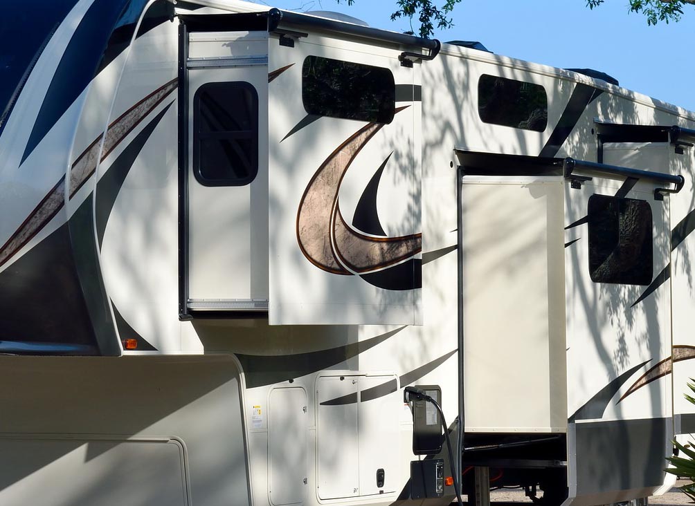 Extended RV slideouts in a shady campground.