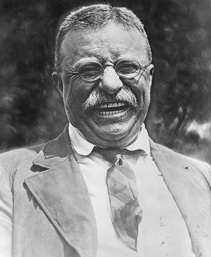 Theodore Roosevelt grins and laughs.