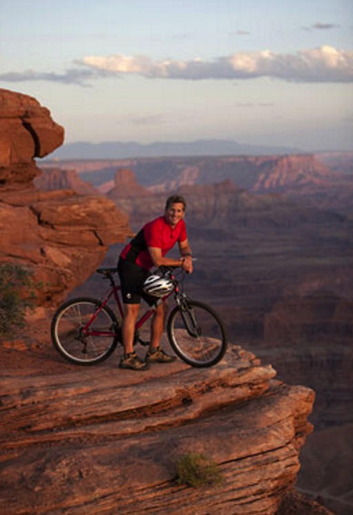 Man sitting on top of bicycle on edge of cliff in Canyonlands National Park