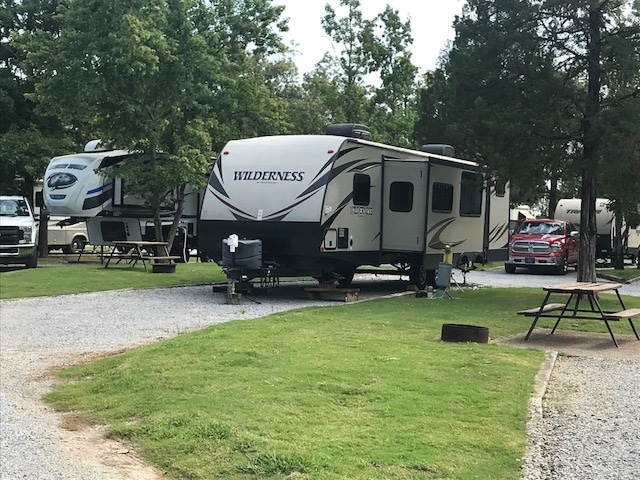Large gray and brown trailer backed into RV spot at campground
