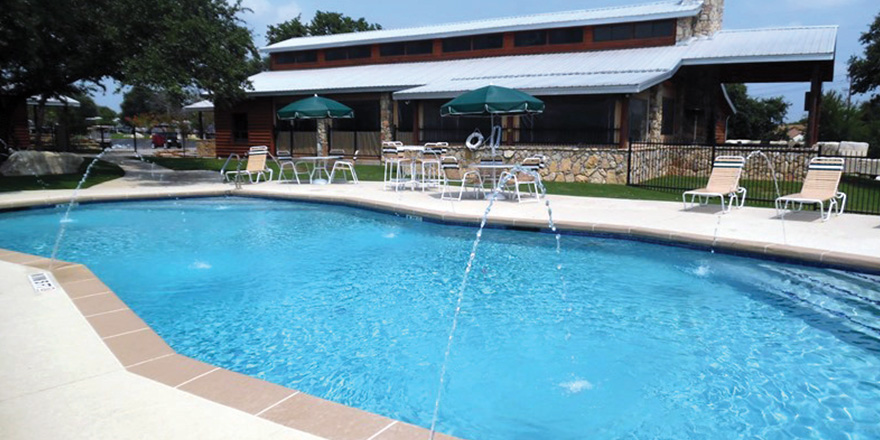 A pool with deck chairs and structure at in the La Hacienda RV Resort.