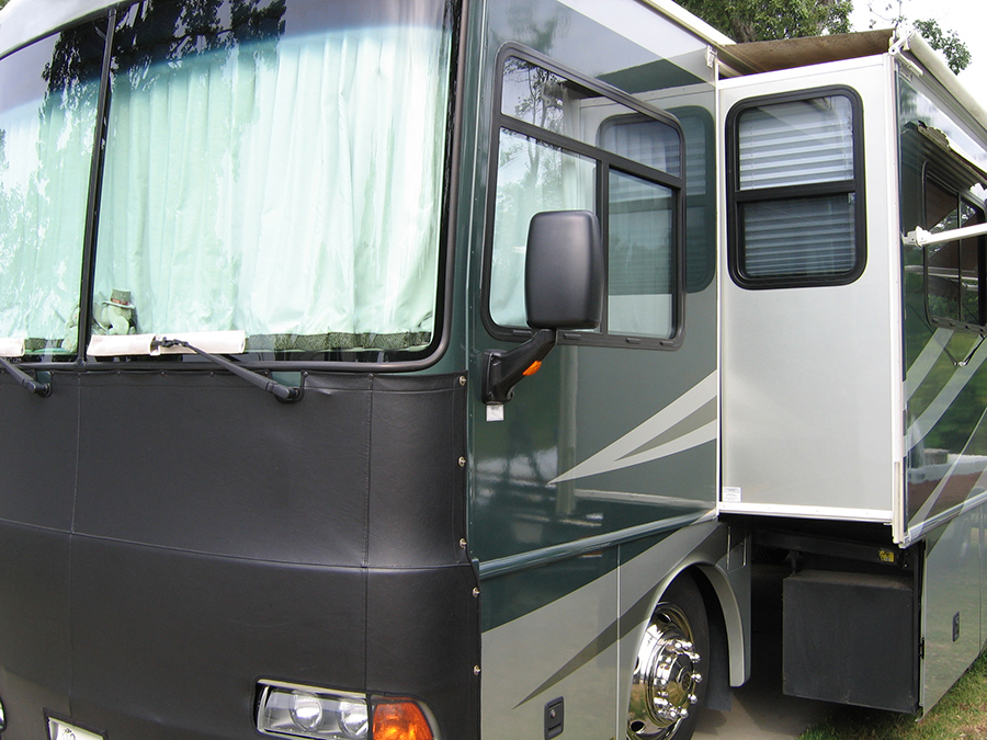 A close-up shot of a motorhome with left-side slide deployed along with storage tray.
