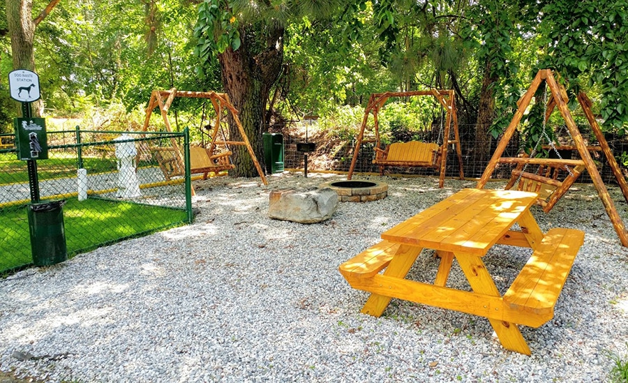 An RV site with a dog run, three swingsets and a picnic table.