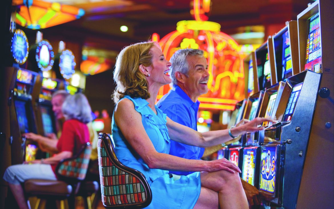 Couple playing slots in large colorful casino