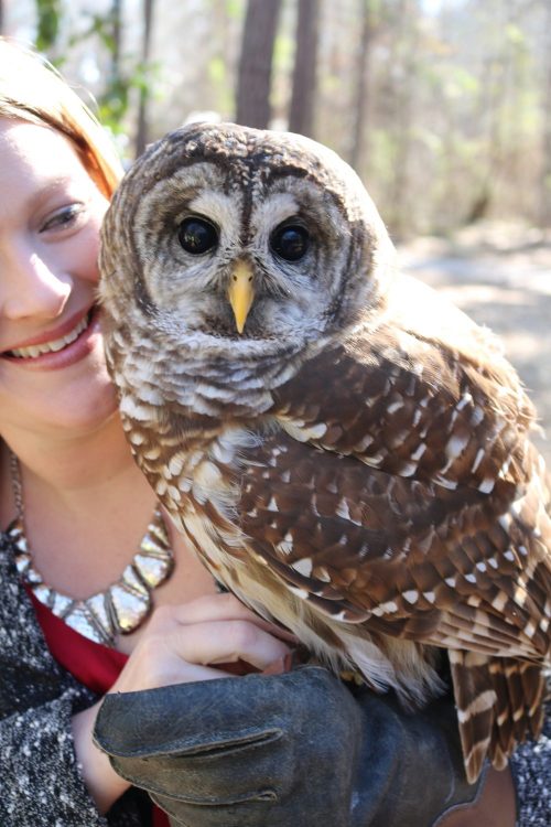 Young woman holding an owl staring at the camera