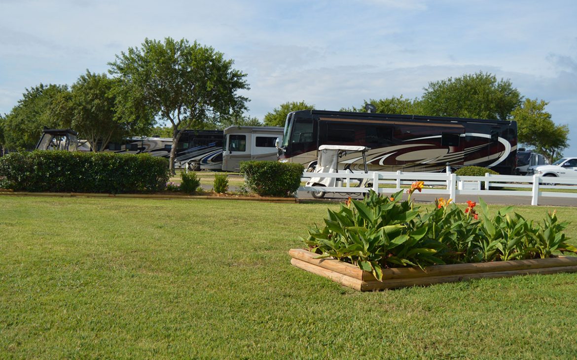 Well groomed lawn and flowers with large RV in background
