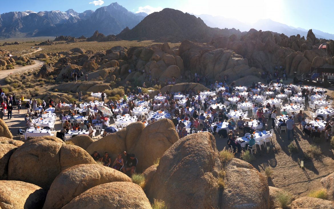 Aerial view of countless people enjoying a concert from tables and tents setup in the rocks