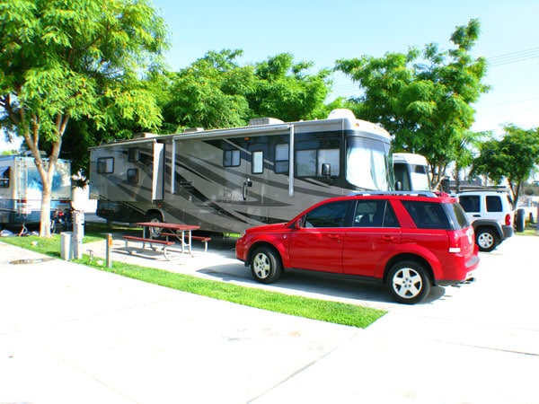 Red Saturn Vue parked in front of large RV