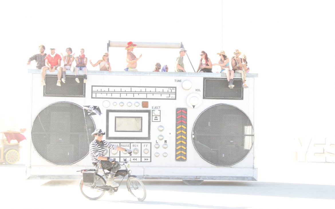 Stereo art car at Burning Man with people on top