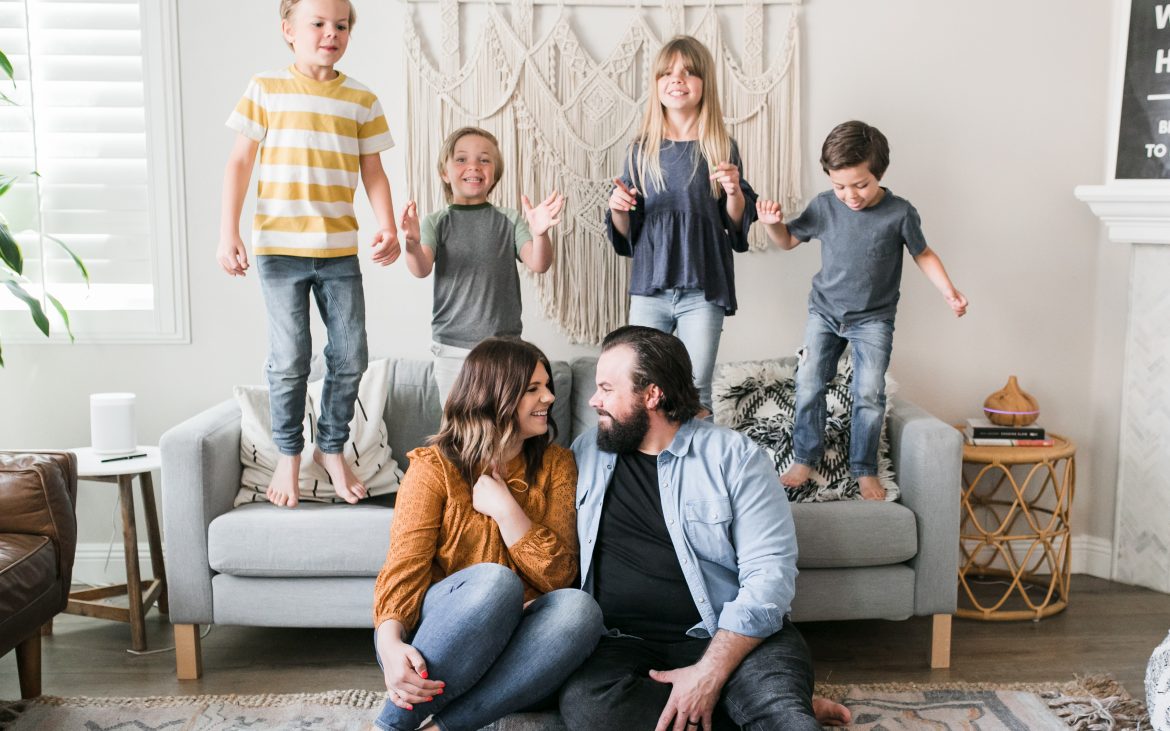 Family of six with four kids standing and jumping on couch