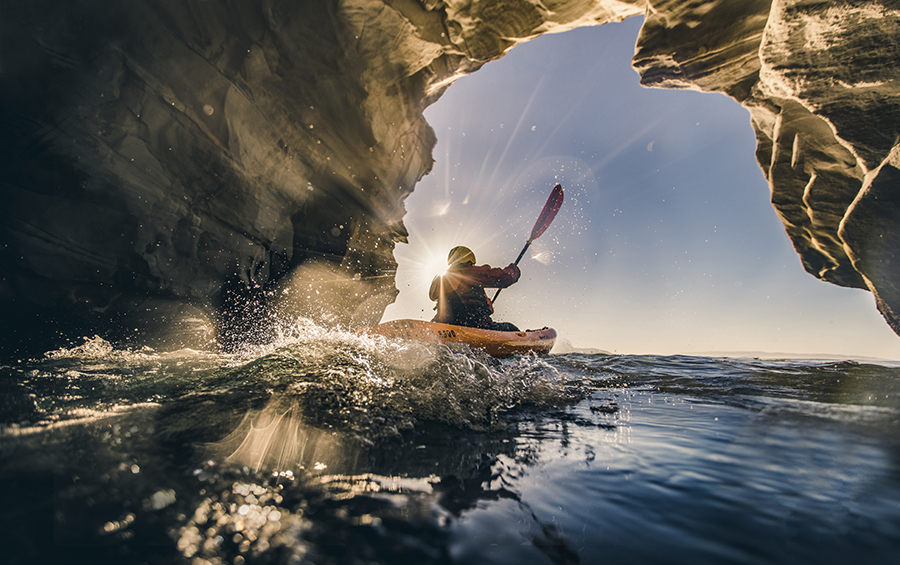 A kayaker exits a cave in the ocean.