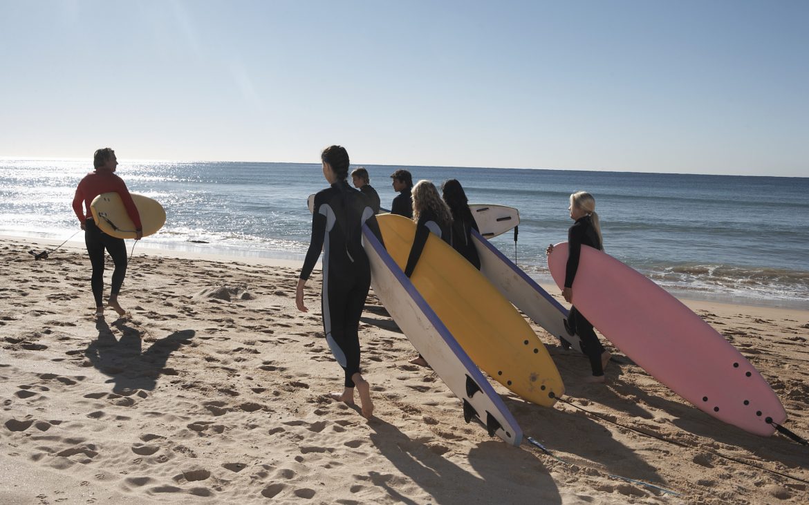 Group of surfers walking on the beach near water
