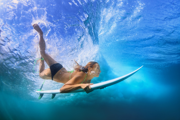 oung active girl in bikini in action - surfer with surf board dive underwater under breaking big ocean wave. Family lifestyle, people water sport adventure camp, beach extreme swim on summer vacation