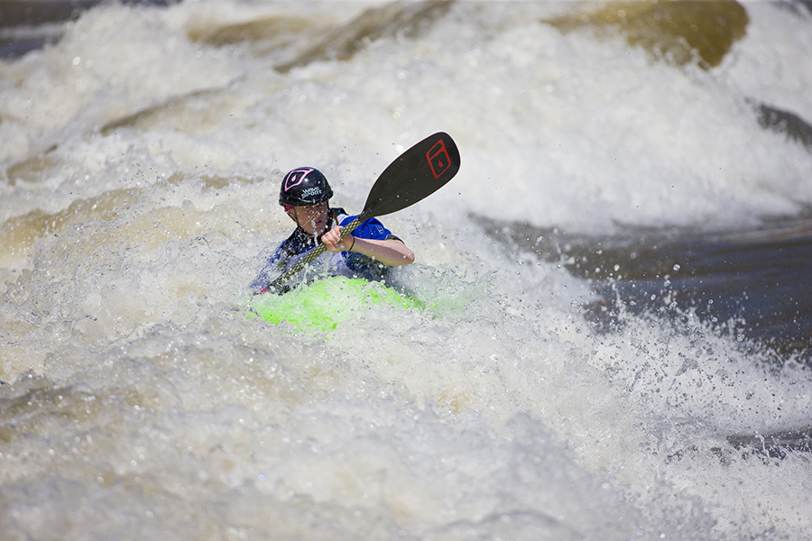 Riding a bright green kayak, a young man navigates frothing rapids in Glenwood Whitewater Park & Activity Area.