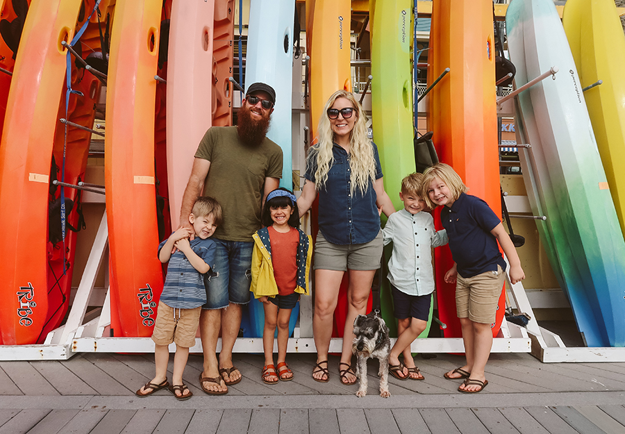 Family of six posing in front of surfboards