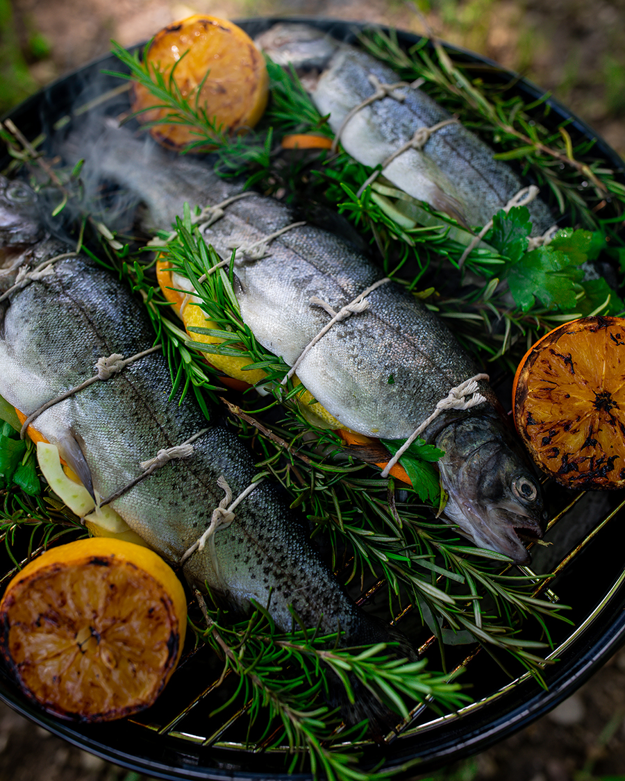 Trout grilling on an barbecue with rosemary and lemons added for flavor.