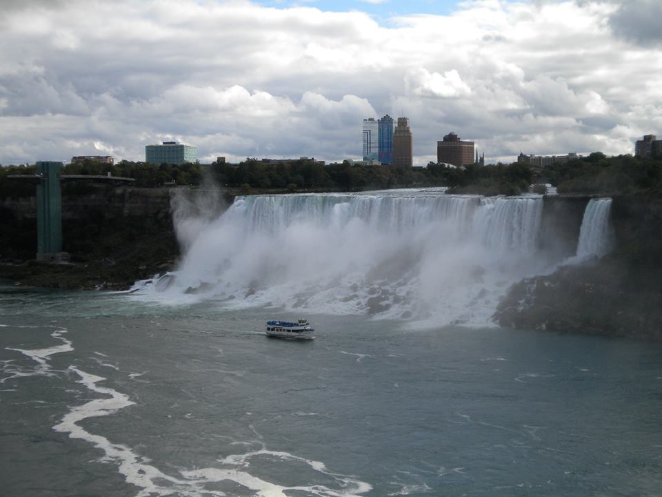 Massive waterfall pouring over behind floating ferry.