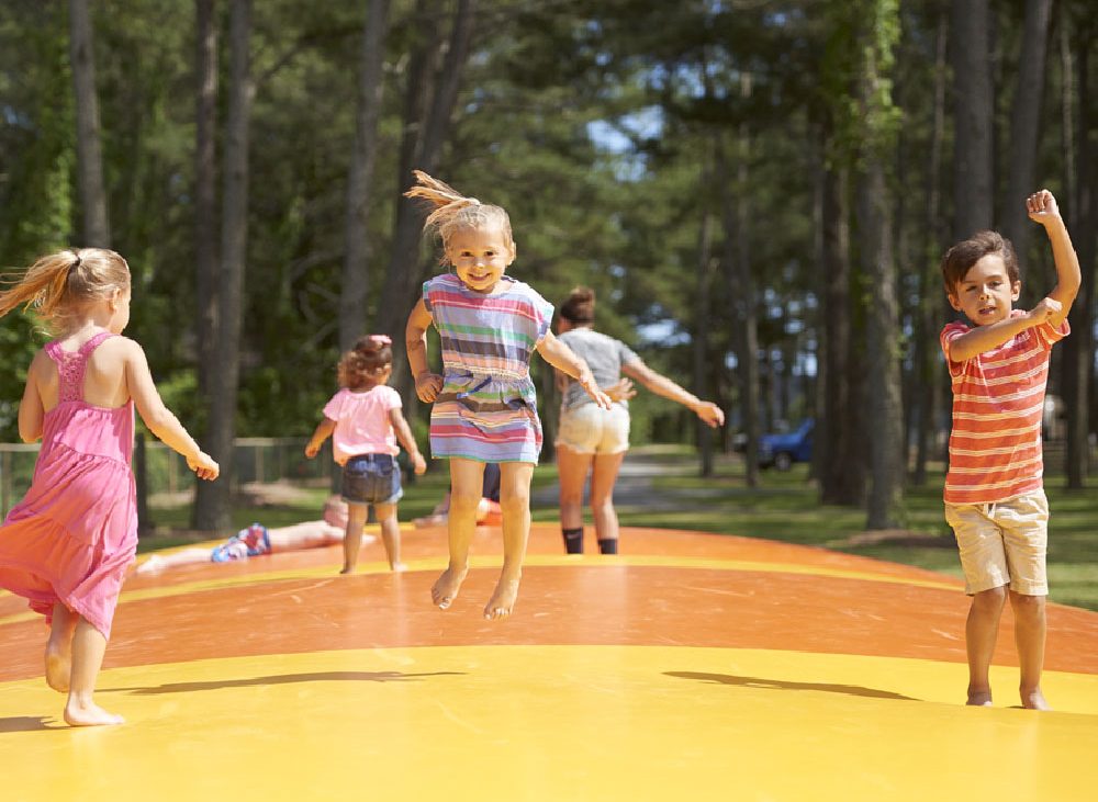 Group of children jumping on orange and yellow pad