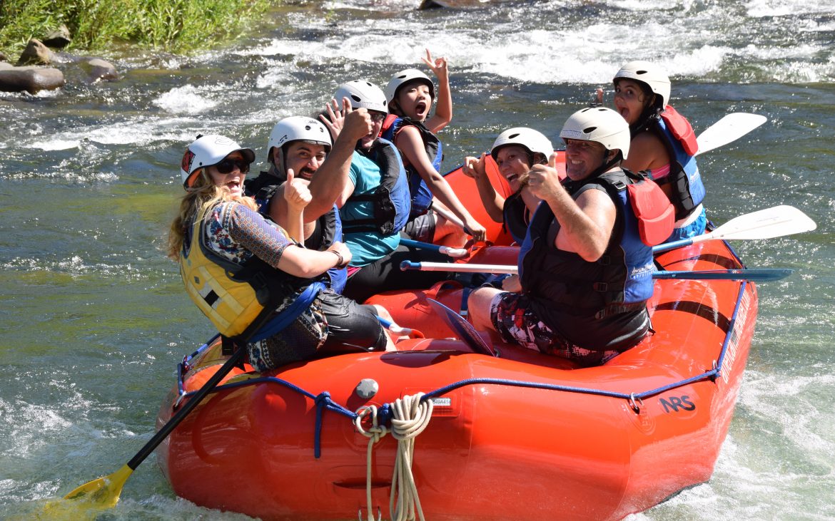 Group of people smiling at camera on raft going down American River