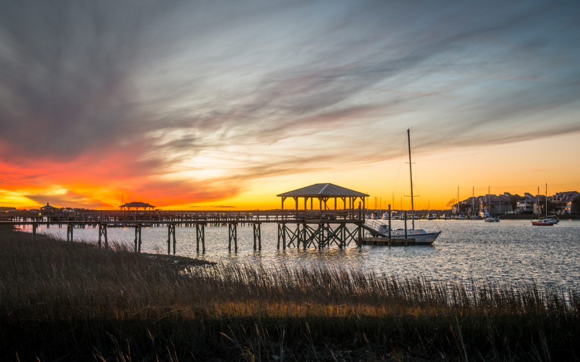 A dramatic sunset rises above residential boat docks at Folly Beach