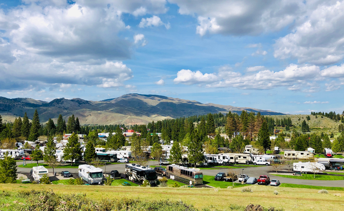 View of RV park amidst mountains and pine trees on beautiful day