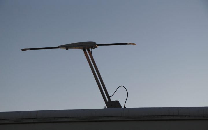 An extended TV antenna on the roof of an RV.