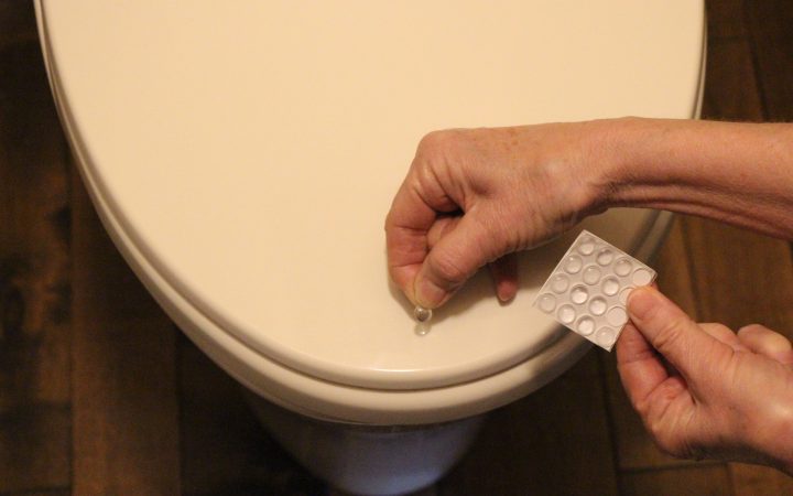 Applying self-adhesive silicone dimples to a toilet lid.