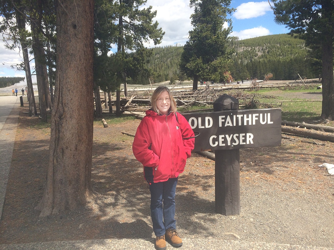 Standing in front of the Old Faithful Geyser sign.