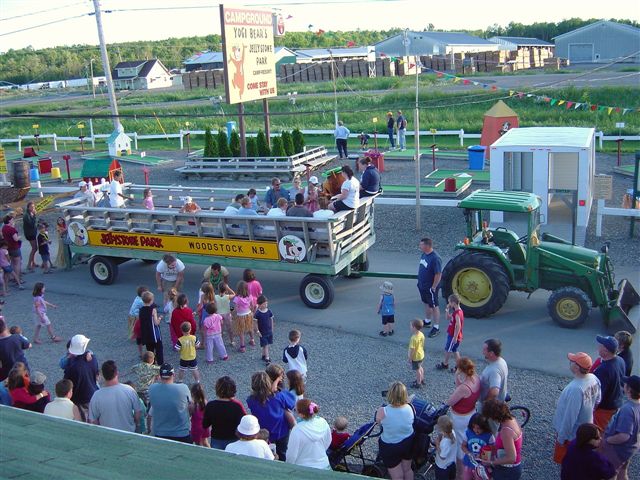 People watching green tractor pulling wagon