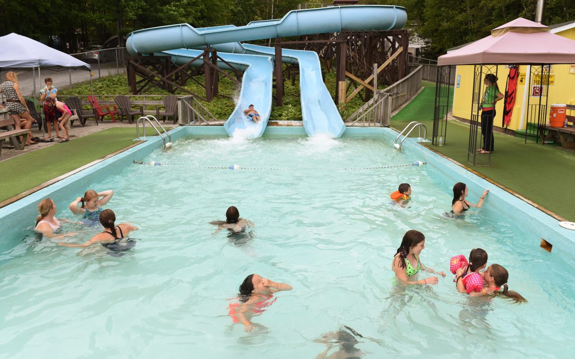 Mothers and children playing in pool at base of blue waterslide
