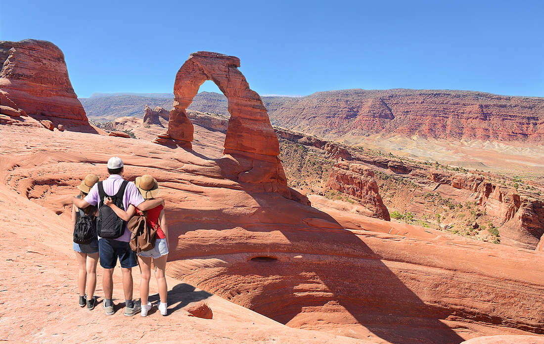 A family hiking on a clear day at Utah's Arches National Park.
