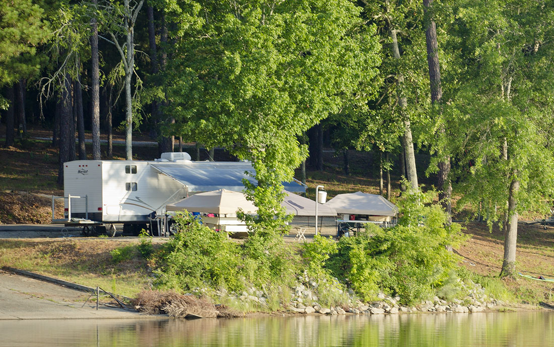 A travel trailer stays cool by camping on the water.