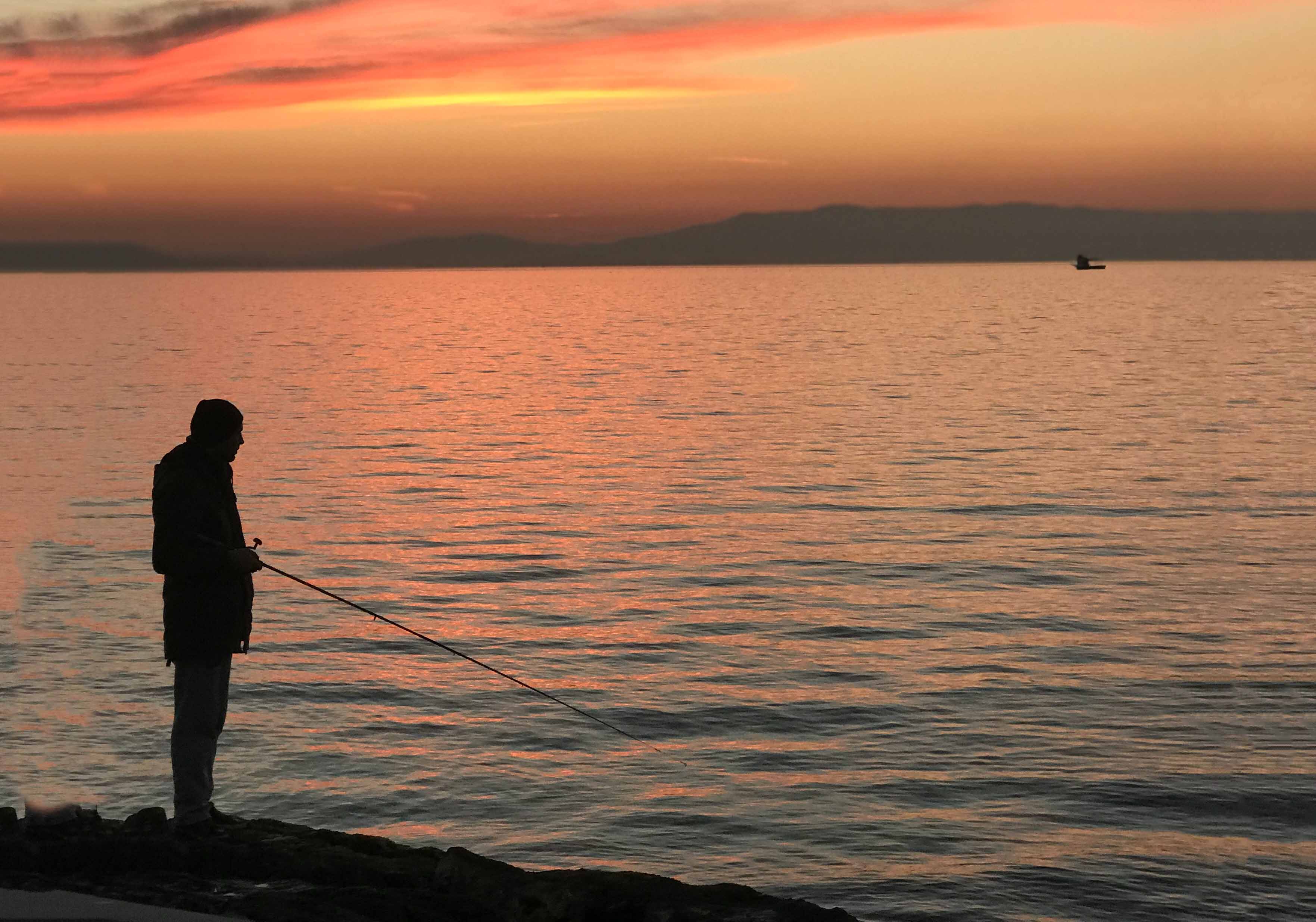 Fishing during dusk on a vast lake.
