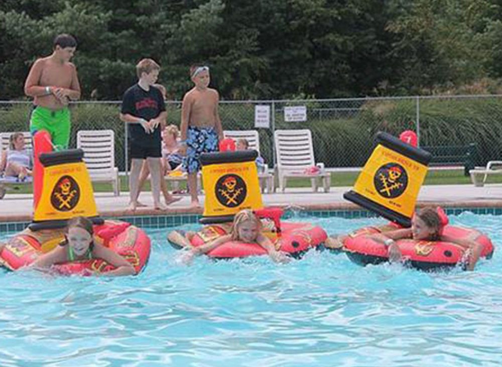 Children playing on red rafts in community pool