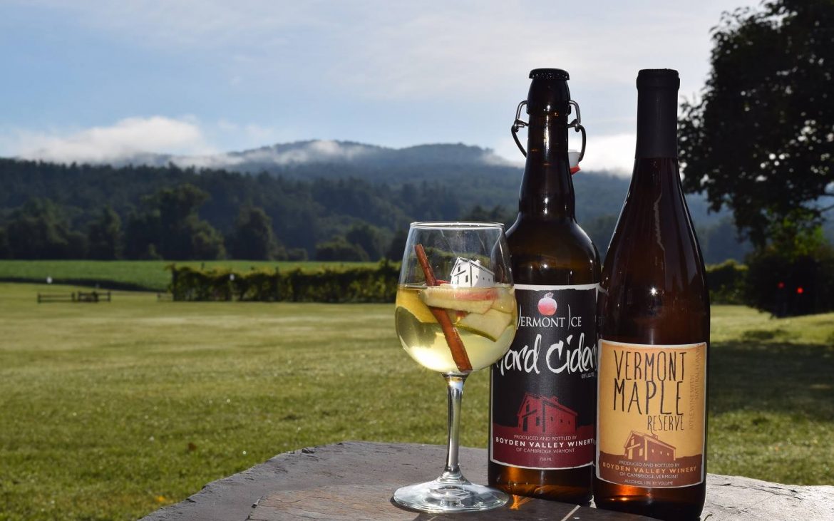 Wine bottles and glass of sangria on table outside at vineyard
