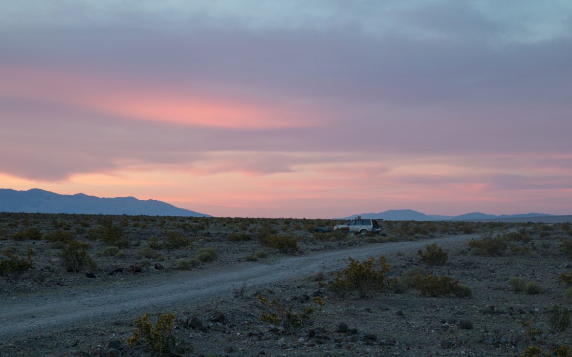 SUV parked in desert at dusk with lavender sky