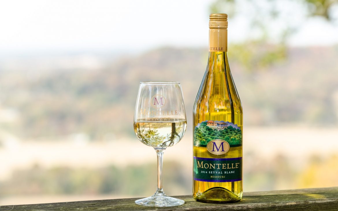 Beautiful glass of while wine with bottle outside on table