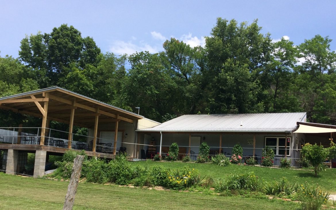 Winery building with outdoor deck and green trees in background